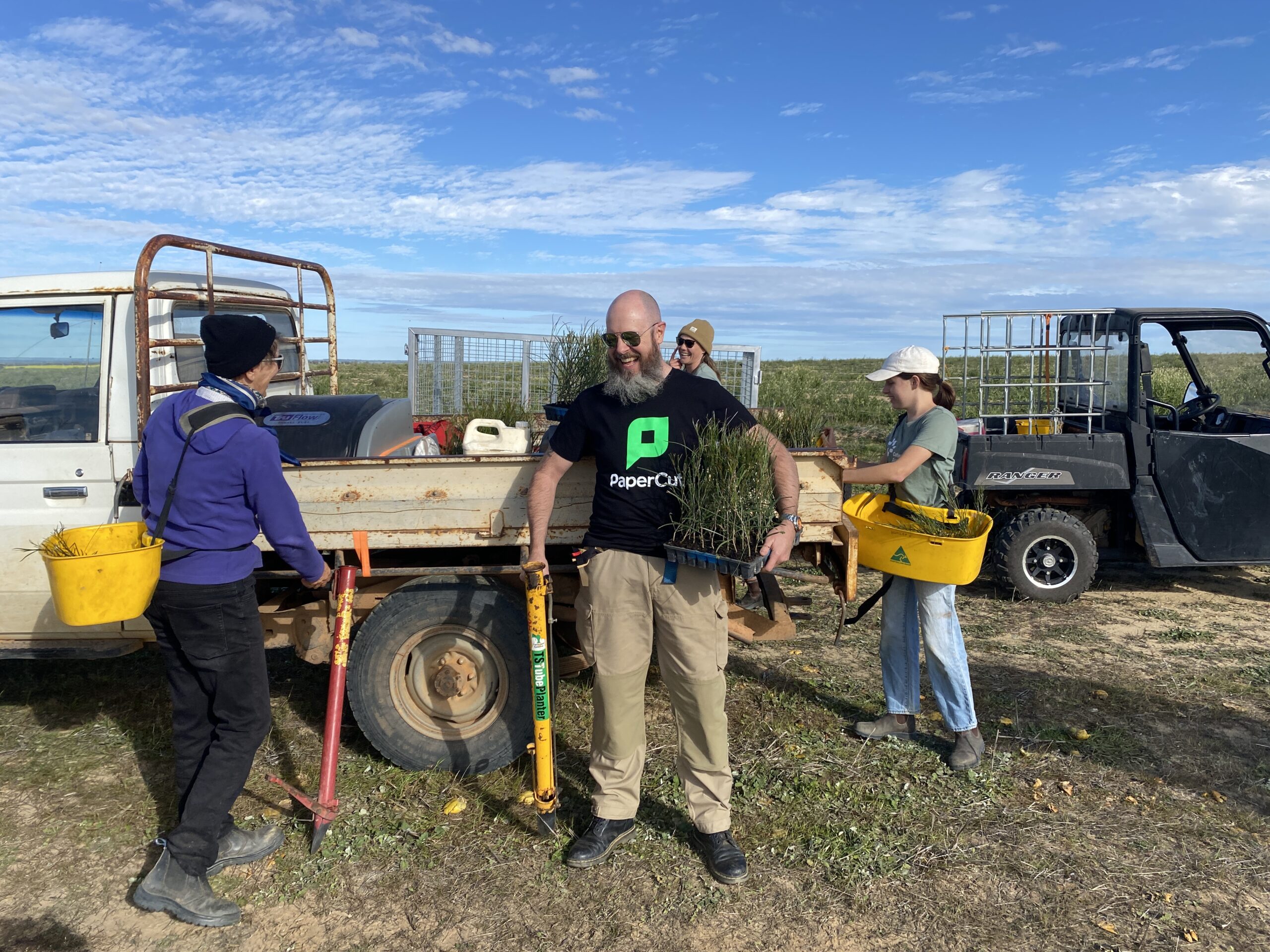 People standing around a white ute with seedlings on the back