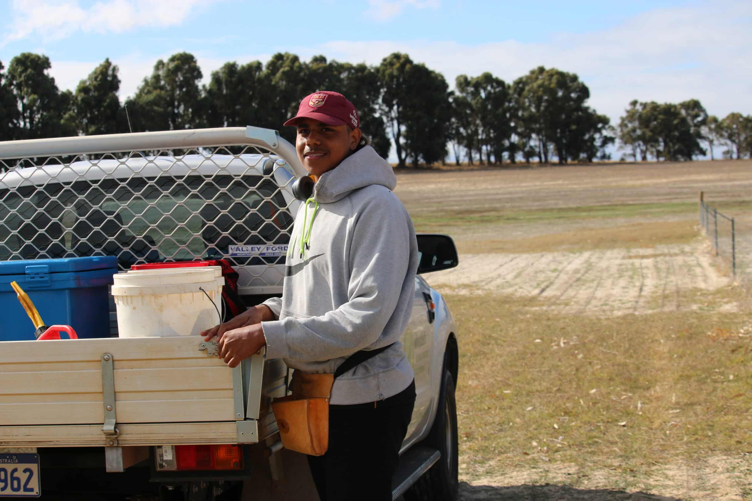 Man standing next to ute tray placing seedlings in seedling bucket