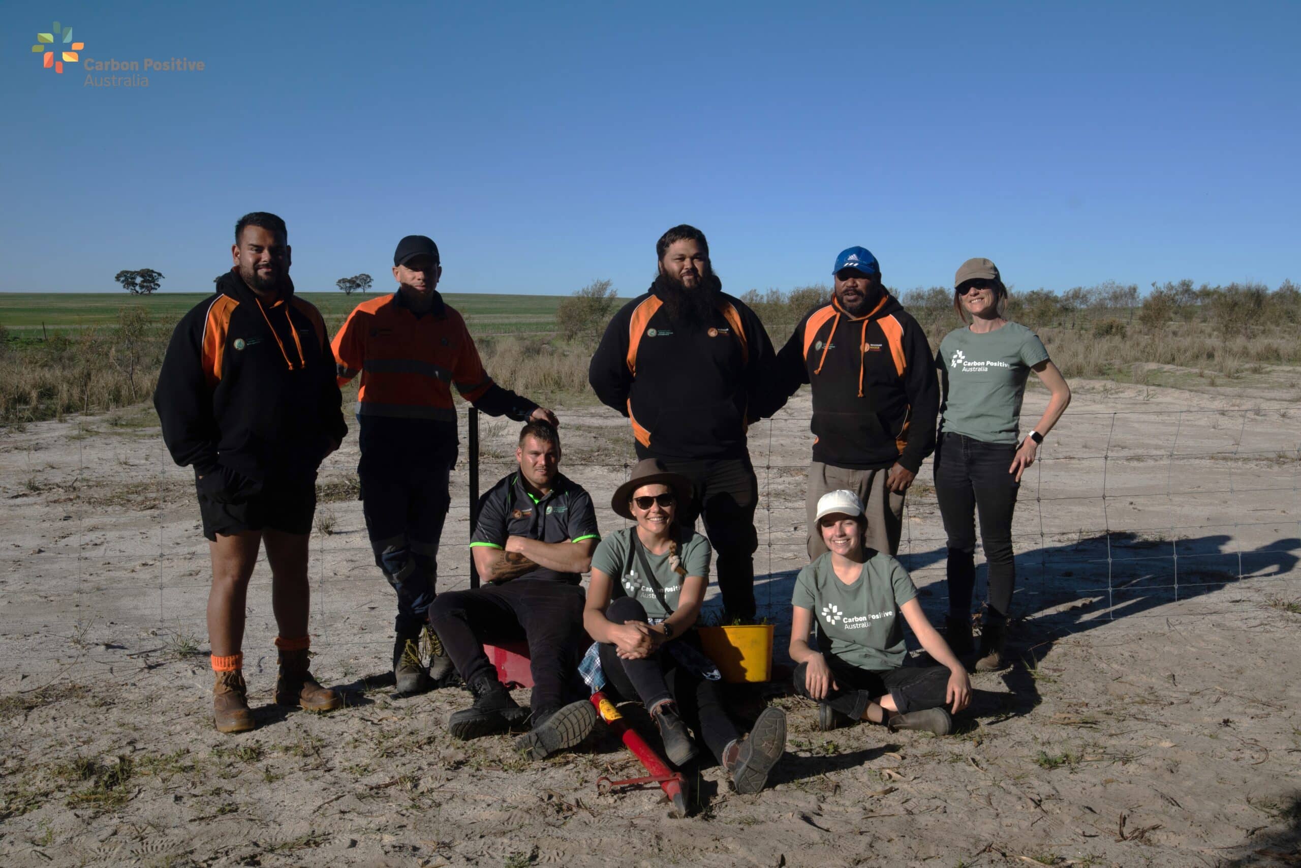 Group photo of planting team standing and sitting on the ground with planting equipment