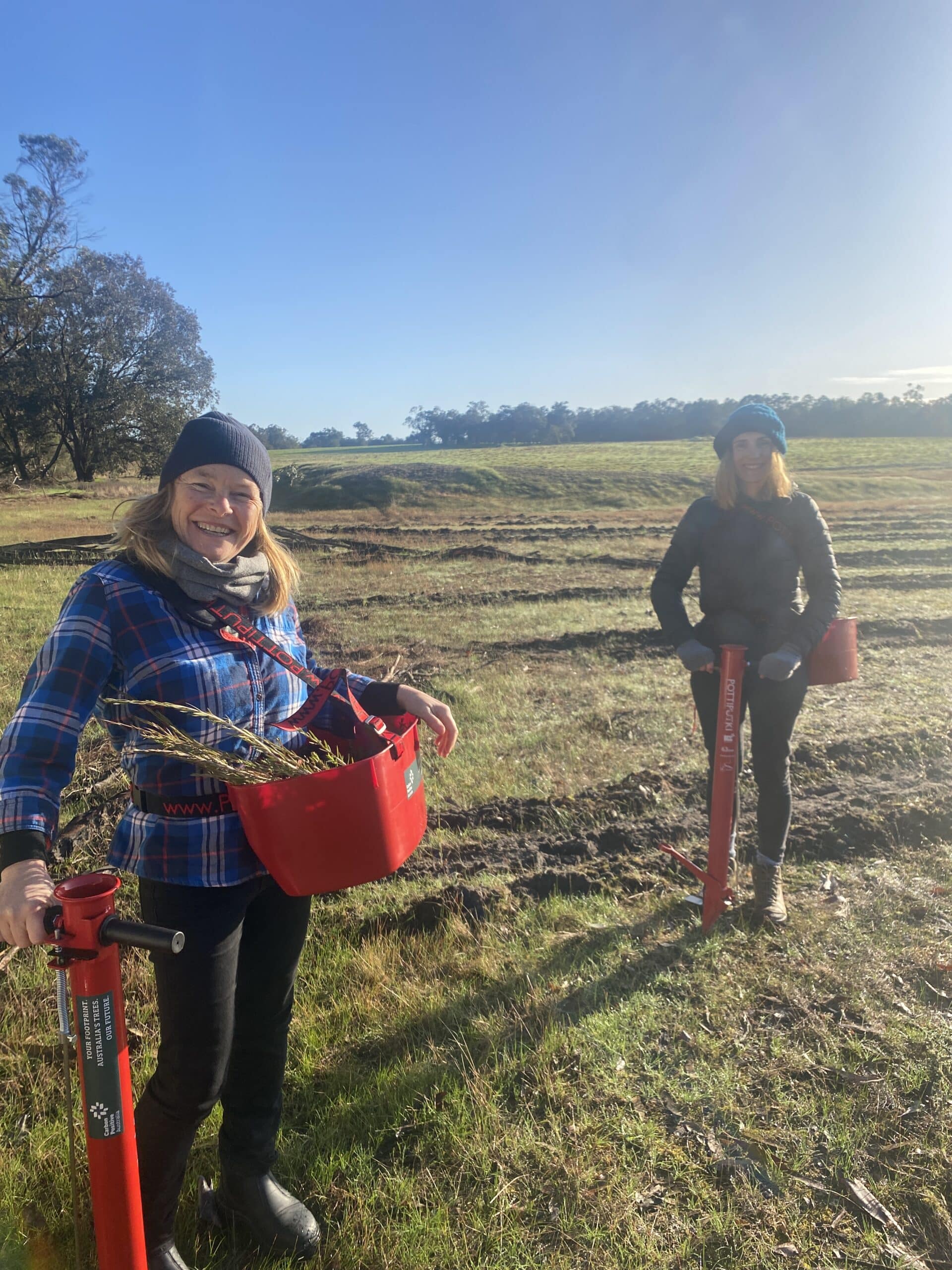 Two women smiling ready to start hand-planting.