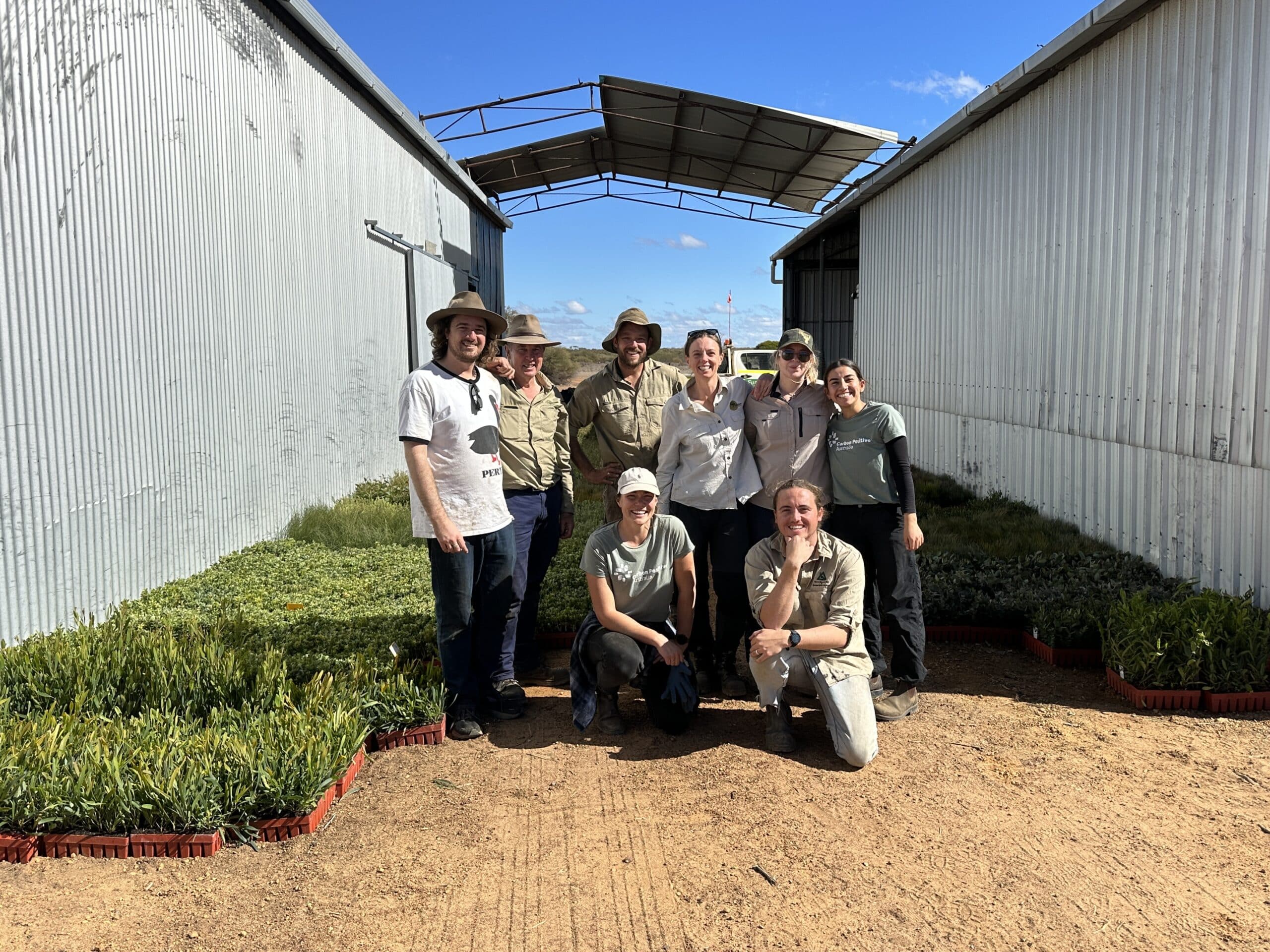 Group photo of planting team in from of seedlings trays