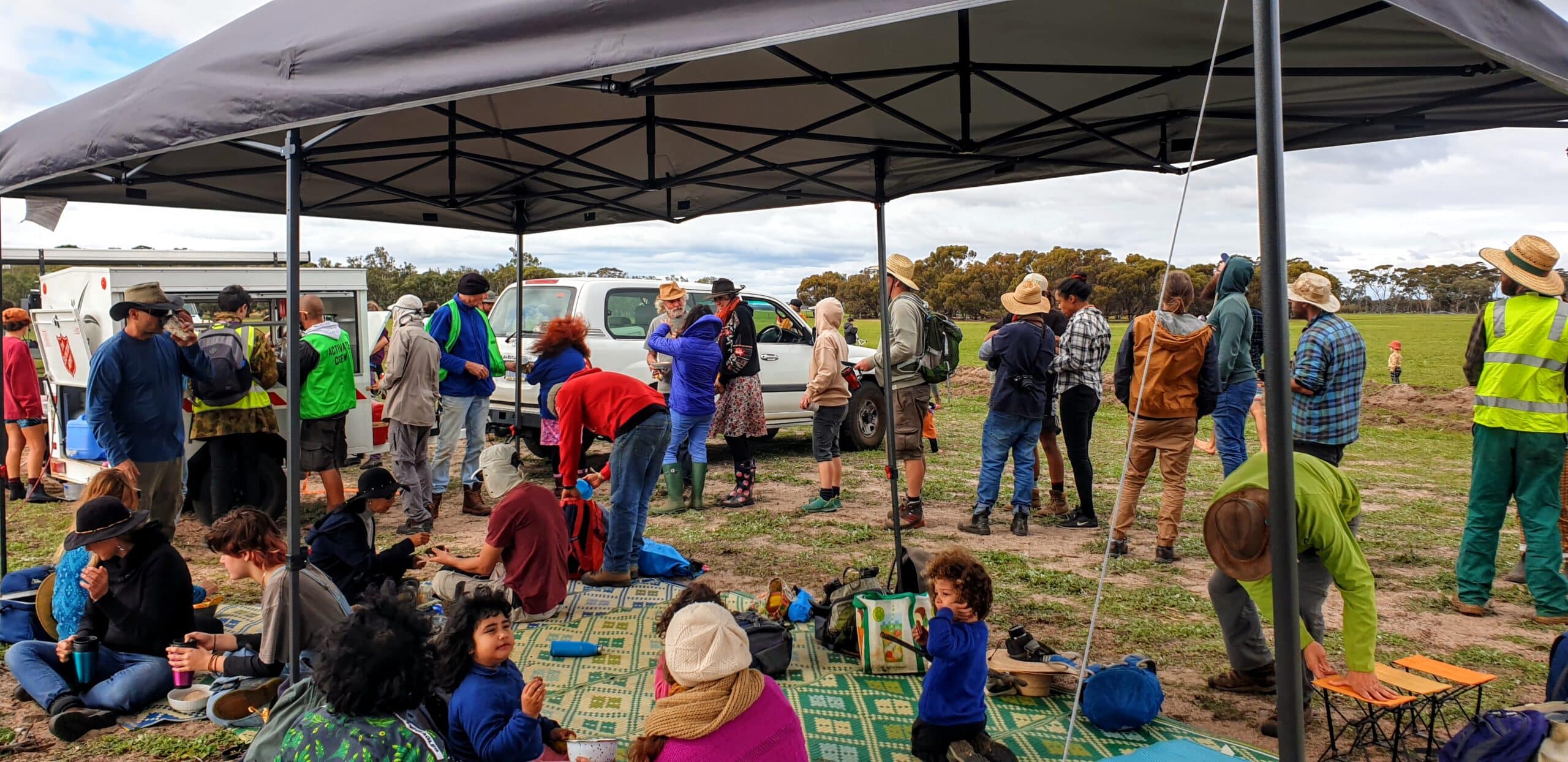 Adults and children sitting and standing under a gazebo