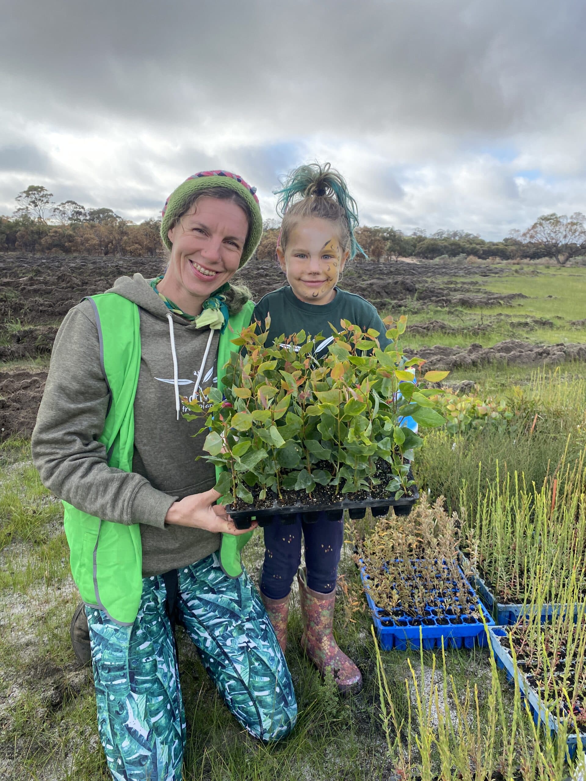 A women and a girl holding a seedling tray