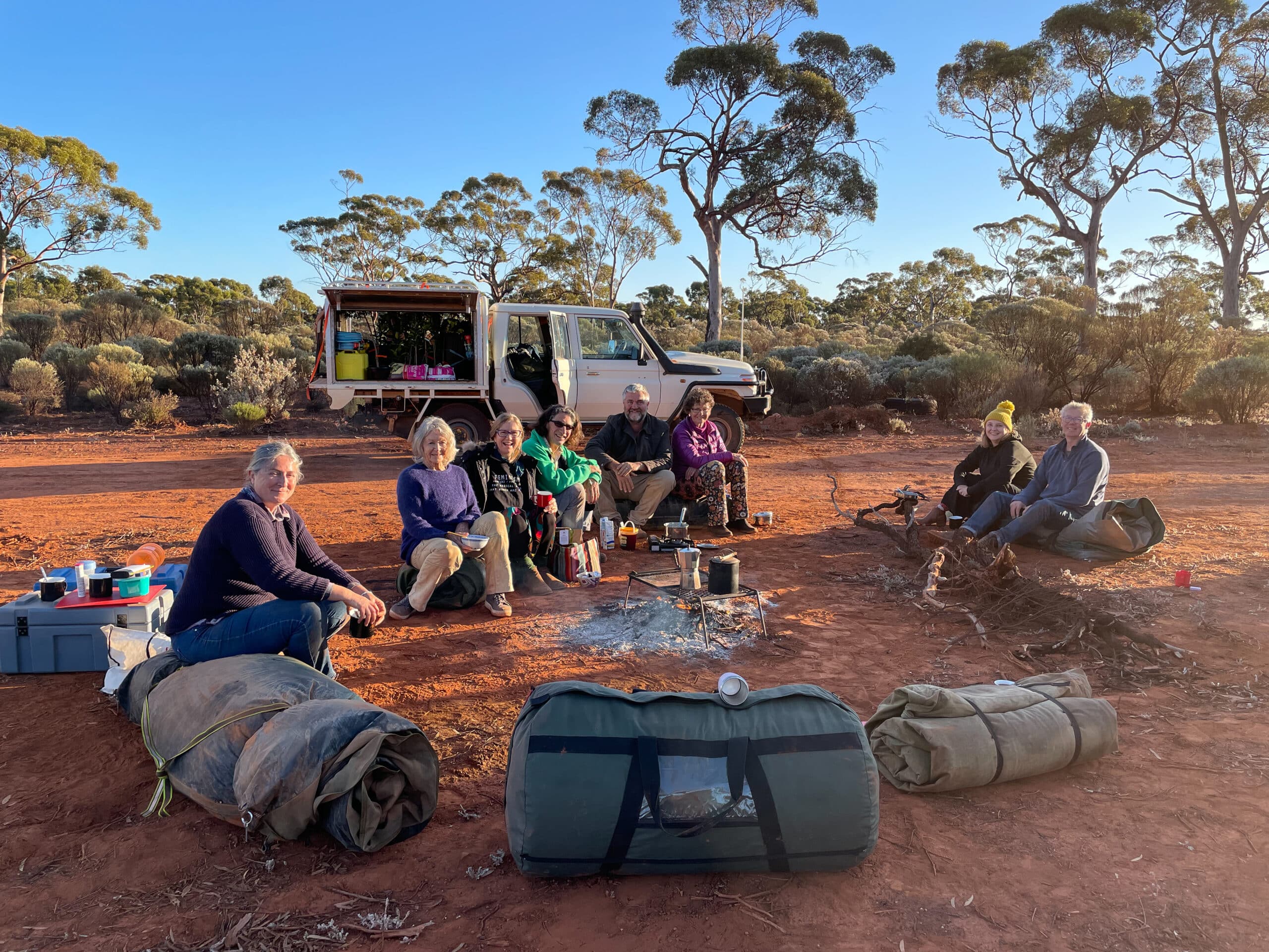 People sitting around a fire with camp gear