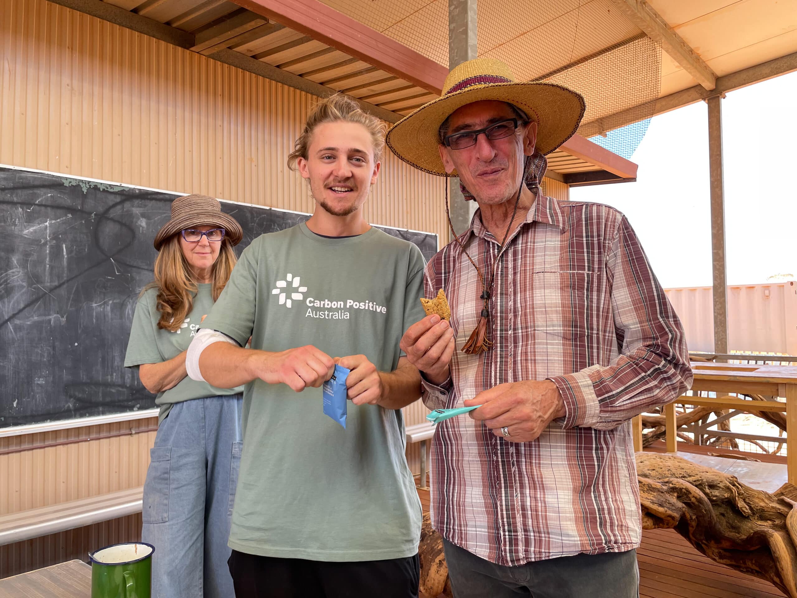 Two men smiling for a photo with a women smiling in the background