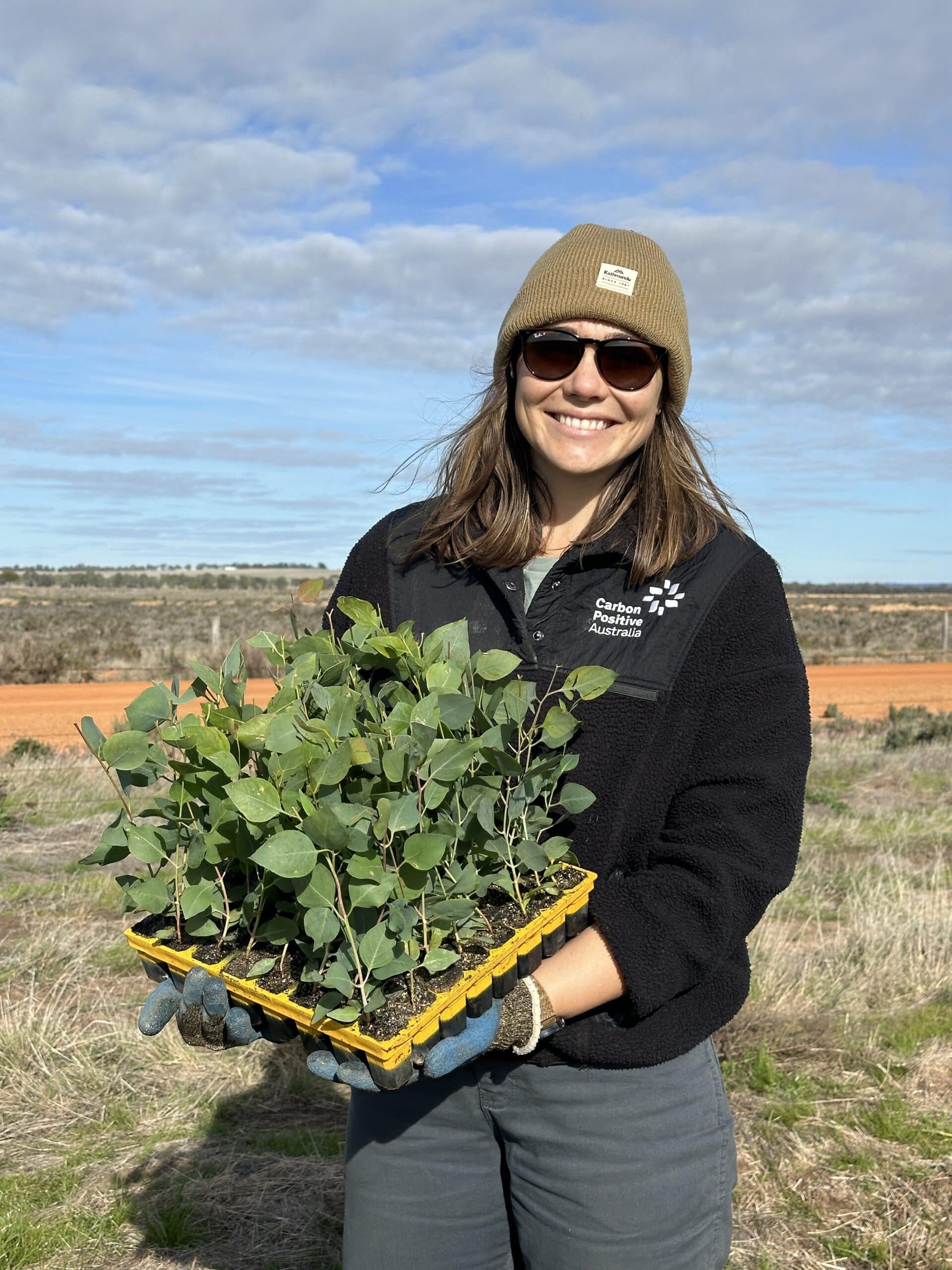 Woman smiling holding a tray of Eucalyptus loxophleba.