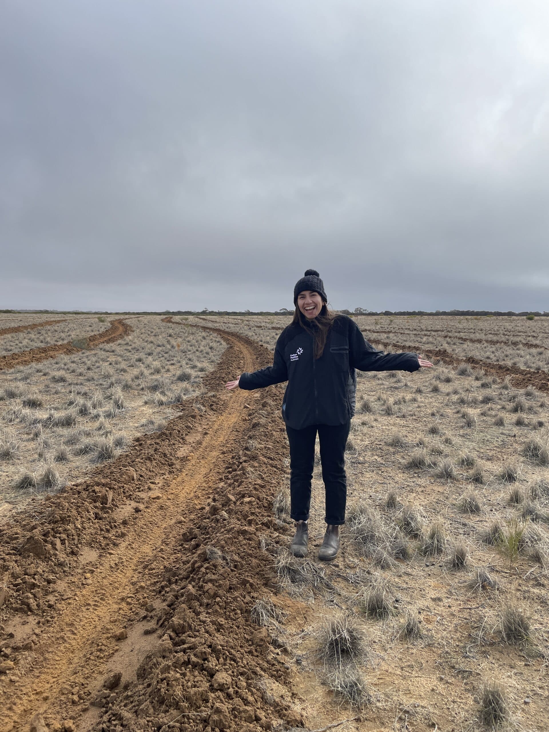 Woman standing in the middle of a paddock with planting rows