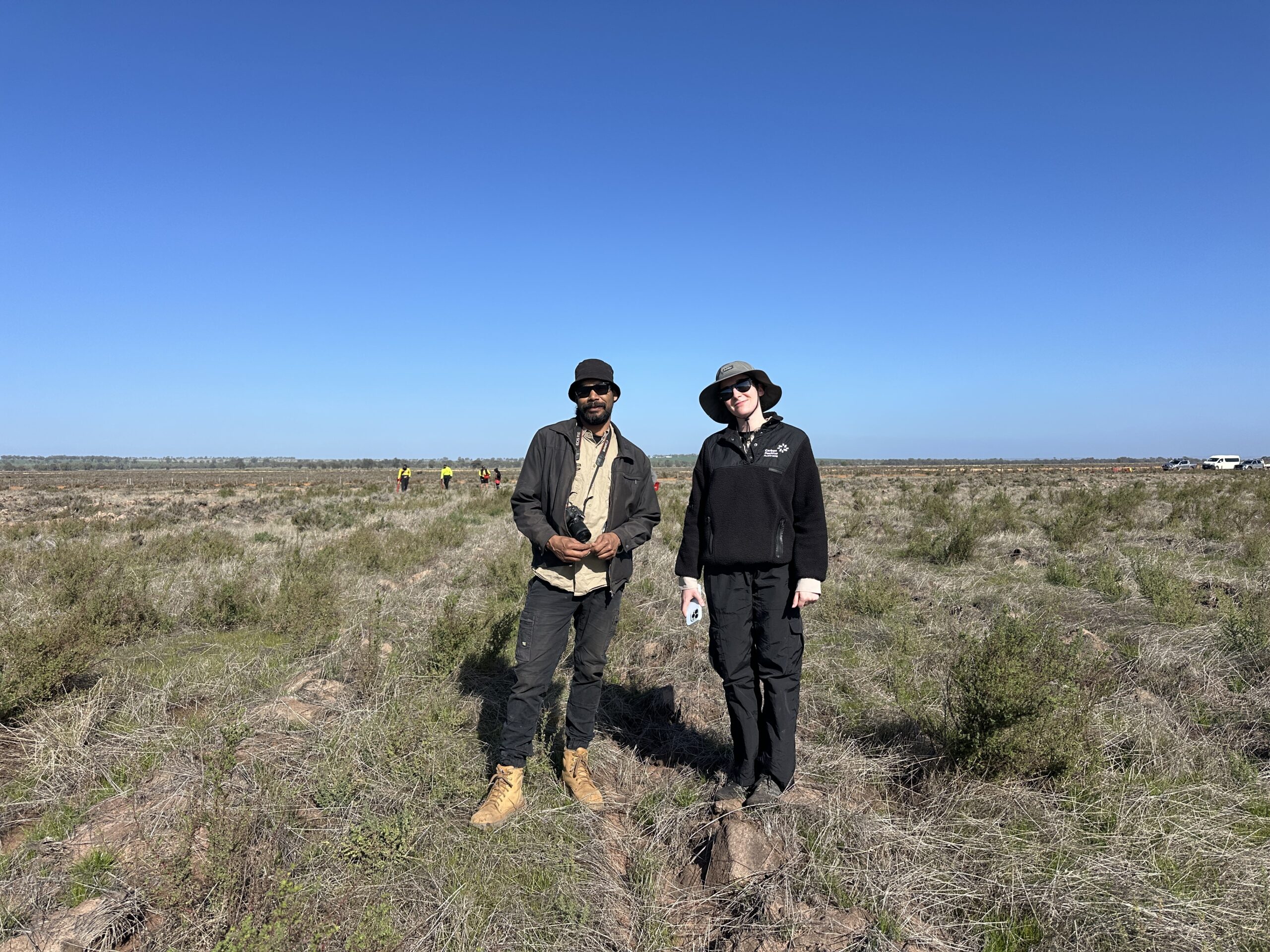 Man and woman with cameras standing in between the planting rows.