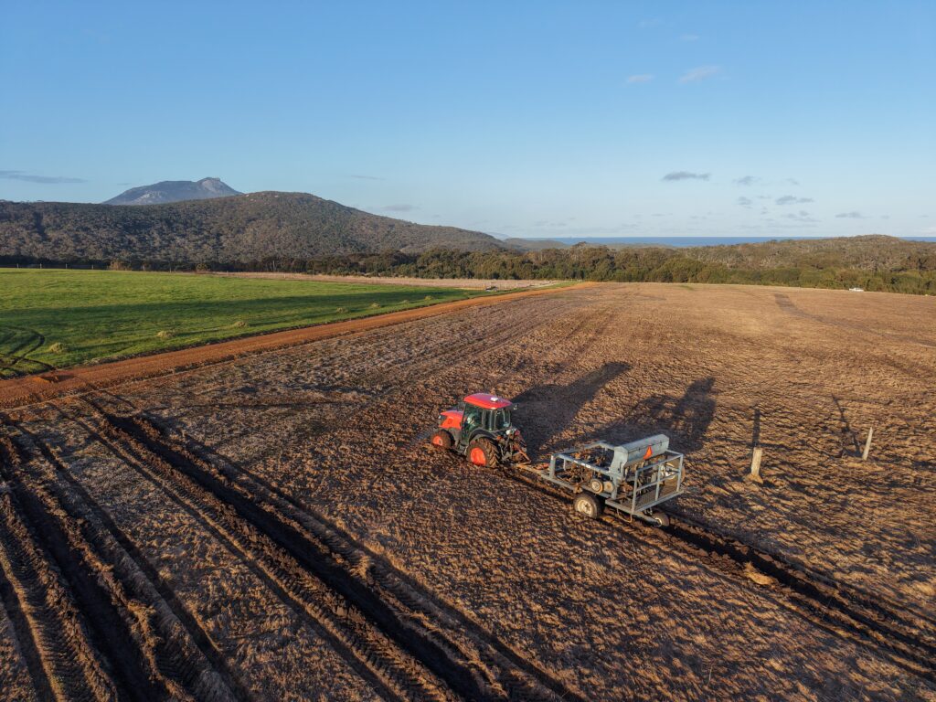 2508_221-Manypeaks-Drone-Photo-6 Drone image of tractor ripping planting lines with mountain in background.